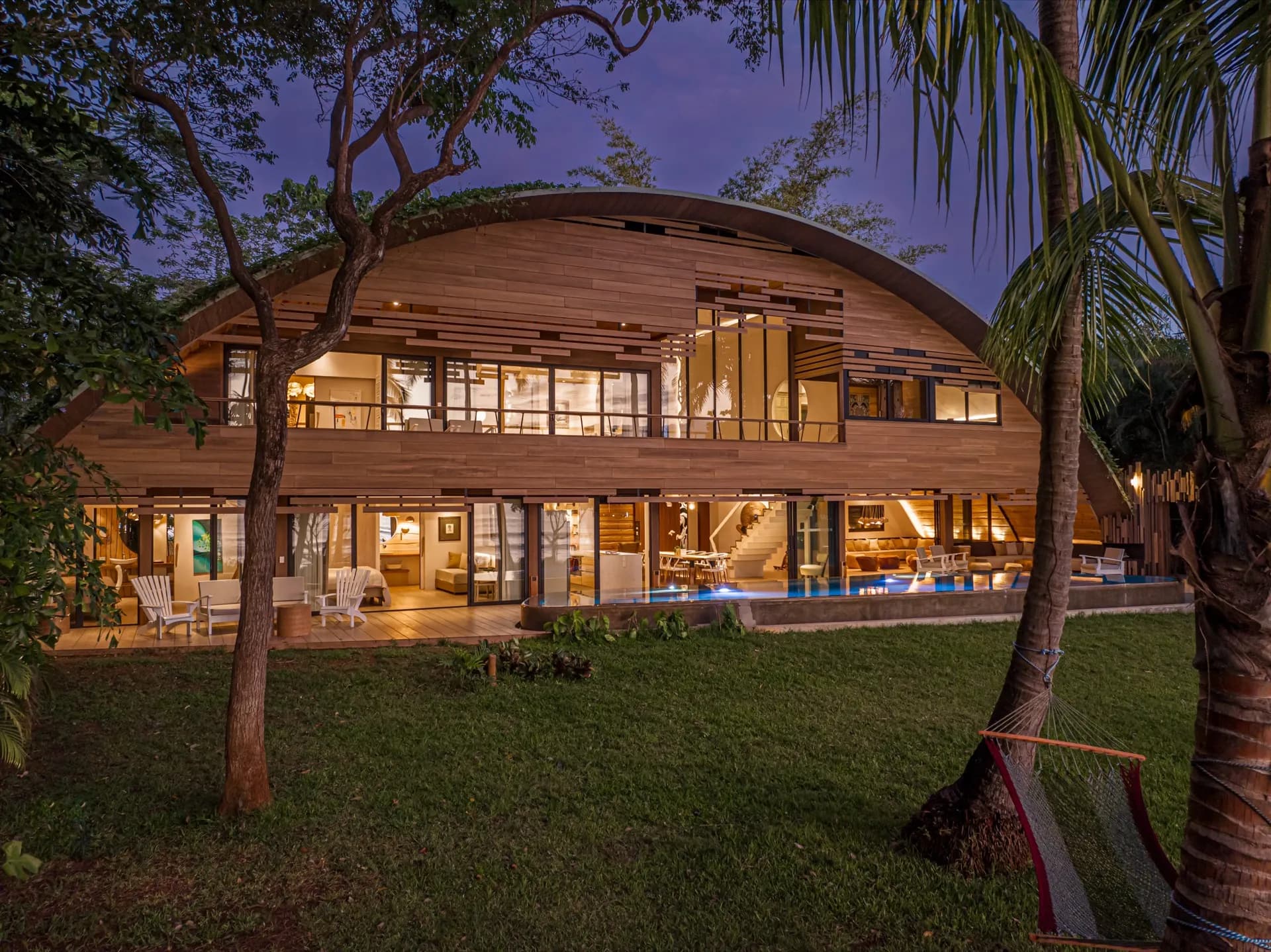 Villa Hermes — the vaulted timber shell of the villa at dusk